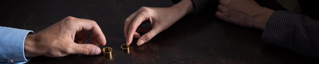 Partial View Of Couple At Table With Divorce Documentsand Rings